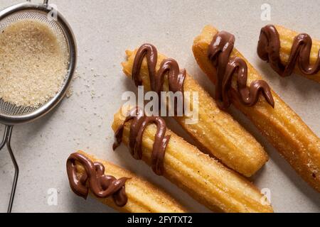 Churros mit Zucker und Schokolade auf hellem Hintergrund. Traditionelles spanisches Fast Food, hausgemachtes Backen. Stockfoto