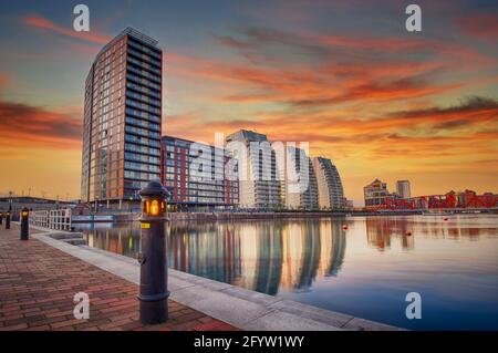 Der Sonnenuntergang über den NV-Gebäuden und einem der Docks in Salford Quays, Salford, Lancashire, Großbritannien Stockfoto