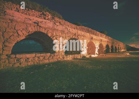 Überreste des antiken römischen Aquädukts in der antiken Stadt Caesarea in der Nacht. Israel. Stockfoto