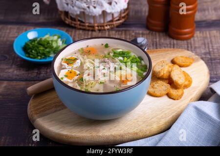 Suppe mit Hühnchen, Nudeln, Kartoffeln, Wachteleiern und Karotten. Gewürzt mit Zwiebeln und Petersilie. Nahaufnahme. Stockfoto