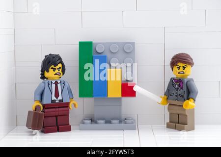Tambow, Russische Föderation - 28. Mai 2021 Lego-Geschäftsleute minifiguren, die ein Treffen abhalten und Diagramme diskutieren, die die Ergebnisse ihrer Untaten zeigen Stockfoto