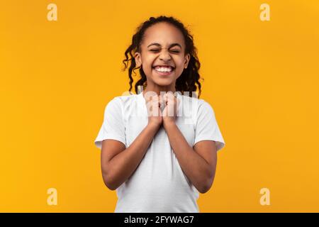 Hoffnungsvolles afroamerikanisches Mädchen, das Wunsch im Studio macht Stockfoto