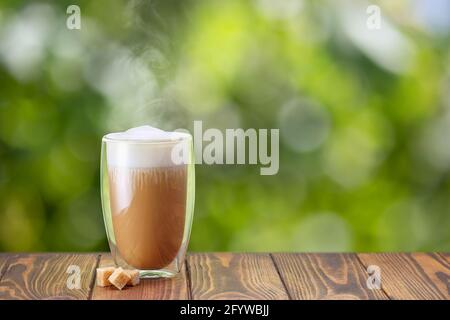Cappuccino in Glas mit Doppelwänden auf dem Tisch Stockfoto