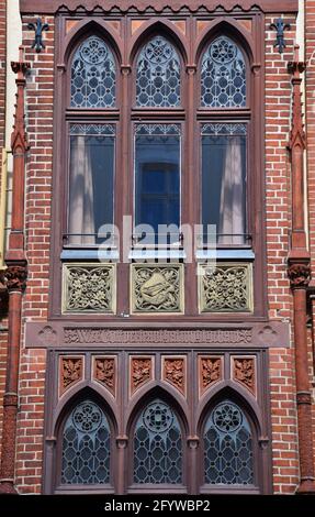Alte, rot gemauerte Fassade mit kunstvoll verzierten Fenstern in Schwerin, Deutschland Stockfoto