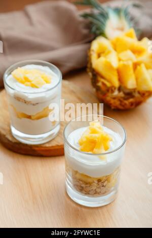 Zwei leckere Ananasdesserts. Frühstücksdessert mit Hafergranola, griechischem Joghurt und Ananas in Glasschichten mit Zutaten frisch saftig gehackt Stockfoto