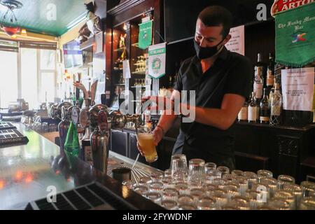 (210530) -- BRÜSSEL, 30. Mai 2021 (Xinhua) -- Luke Nolan arbeitet in der Bar 'Funky Monkey', in Brüssel, Belgien, am 28. Mai 2021. Für Barmanager Luke Nolan kam die Entscheidung der belgischen Regierung, dem Gastgewerbe ab Mai 8 die Freiluftterrasse wieder zu eröffnen, nicht zu früh. Zuvor überlebten Luke und seine Kollegen Monate der harten Handhabung der Bar aufgrund der COVID-19-Pandemie und erspiesten abends Mahlzeiten zum Mitnehmen. „Es war eine große Erleichterung für alle und ausgezeichnet für uns, wieder am Arbeitsplatz zu sein und hervorragend für unsere psychische Gesundheit. Für die Menschen ist es großartig, wie sie Stockfoto