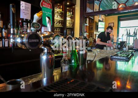 (210530) -- BRÜSSEL, 30. Mai 2021 (Xinhua) -- Luke Nolan arbeitet in der Bar 'Funky Monkey', in Brüssel, Belgien, am 28. Mai 2021. Für Barmanager Luke Nolan kam die Entscheidung der belgischen Regierung, dem Gastgewerbe ab Mai 8 die Freiluftterrasse wieder zu eröffnen, nicht zu früh. Zuvor überlebten Luke und seine Kollegen Monate der harten Handhabung der Bar aufgrund der COVID-19-Pandemie und erspiesten abends Mahlzeiten zum Mitnehmen. „Es war eine große Erleichterung für alle und ausgezeichnet für uns, wieder am Arbeitsplatz zu sein und hervorragend für unsere psychische Gesundheit. Für die Menschen ist es großartig, wie sie Stockfoto