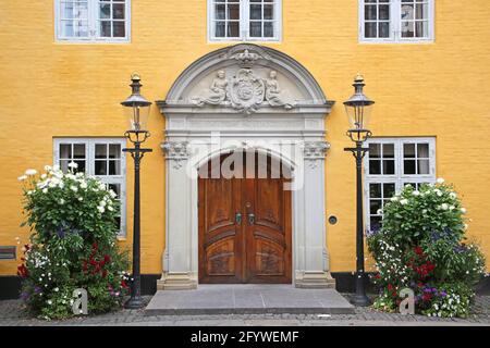 Eingangstor zum Alten Rathaus. Schönes historisches, gelb gestrichenes Gebäude mit einer Holztür im Stadtzentrum von Aalborg, Dänemark. Stockfoto