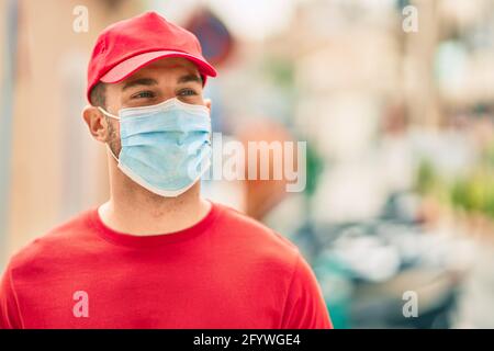Der junge kaukasische Retter trägt eine medizinische Maske und steht vor der Stadt. Stockfoto