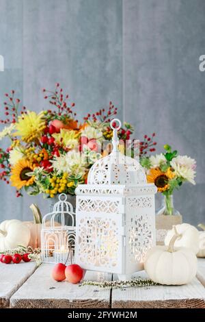 Schöne weiße Laterne, Blumen und Kürbisse auf dem Tisch. Romantische Herbstdekoration. Stockfoto