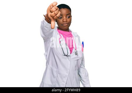 Junge afroamerikanische Frau in Ärzteuniform und Stethoskop, die unglücklich und wütend aussagt und mit Daumen nach unten ablehnend und negativ aussagt. Stockfoto