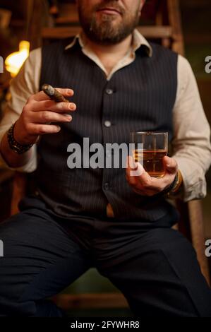 Mann raucht eine Zigarre und trinkt Alkoholgetränke Stockfoto