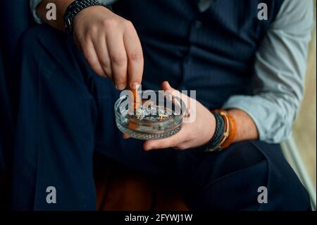 Mann legt eine Zigarre in einen Aschenbecher, Nahaufnahme Stockfoto