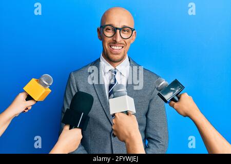 Glatze Mann mit Bart von Reportern mit Mikrofonen mit einem glücklichen und kühlen Lächeln auf dem Gesicht interviewt. Glückliche Person. Stockfoto