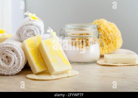 Handgemachte Seife, Spa-Bad Produkte Aroma Salz, weiße Handtücher tropischen Blumen Zusammensetzung auf Marmortisch. Startseite Beauty-Kosmetik-Produkte für Entspannung Stockfoto