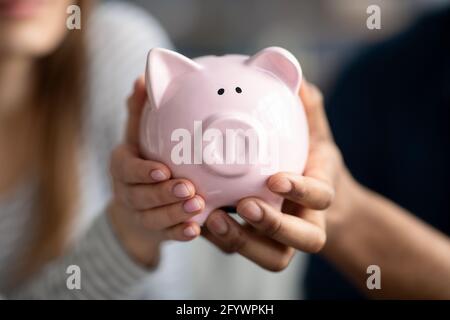 Unbekanntes Paar, Das Rosa Sparschwein In Den Händen Hält Und Geld Für Die Zukunft Spart Stockfoto