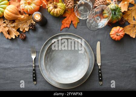 Herbst- und Thanksgiving-Tagestisch mit leerem Teller als Mockup verzierte Blätter, Kürbisse, stilvoller grauer Teller und Tischdecke. Draufsicht. Stockfoto
