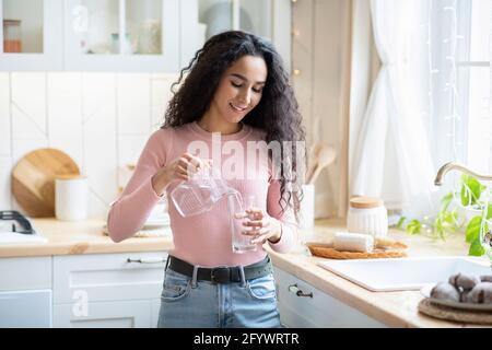 Schöne Junge Dame, Die Wasser Aus Dem Krug Ins Glas Gießt Küche Stockfoto