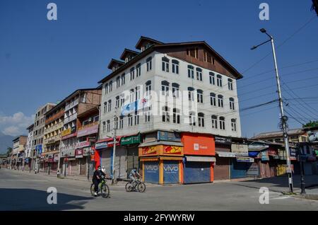 Srinagar, Indien. Mai 2021. Radler mit Gesichtsmasken fahren während einer Sperre durch eine verlassene Straße, um die Ausbreitung des Coronavirus in Srinagar zu verhindern. Die Regierung hat am Sonntag eine Lockerung der Lockdown-Richtlinien in Jammu und Kaschmir vom Montag an angeordnet, während die Bildungseinrichtungen bis zum 15. Juni geschlossen bleiben sollen. Indes verzeichnete Indien einen Tagesanstieg von 165,553 neuen COVID-19-Fällen, der niedrigste seit 46 Tagen mit 3,460 Todesfällen in den letzten 24 Stunden. Kredit: SOPA Images Limited/Alamy Live Nachrichten Stockfoto