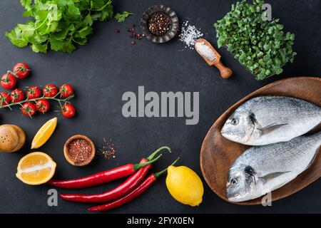 Food Frame ungekochte Fische und Zutaten Gemüse, Gewürze und Gemüse auf schwarzem Schiefer Hintergrund, Draufsicht, Kopierraum. Gesundes Kochen Stockfoto