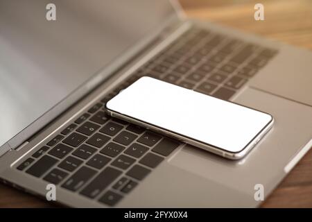 Modernes Smartphone mit leerem Bildschirm auf Laptop-Computer-Tastatur, Modell für Design oder Werbung auf Handy platziert Stockfoto