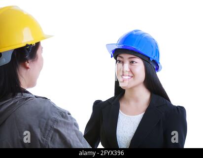 Asiatischer Ingenieur im Gespräch mit Bauarbeiter. Schöne und selbstbewusste junge Architektin, die einen blauen Helm trägt und lächelt. Isoliert auf weiß b Stockfoto