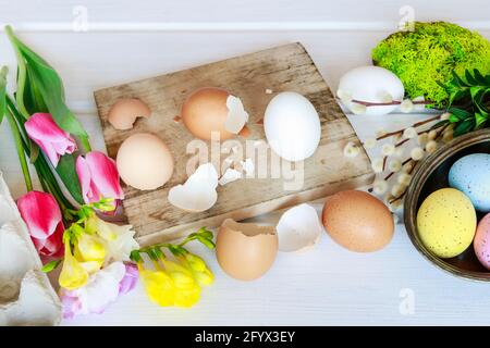 Floristin bei der Arbeit: Frau zeigt, wie man Ostern Blumenschmuck mit bunten Eiern, Tulpen, Freesias und Buxus zu machen. Schritt für Schritt, Tutorial. Stockfoto