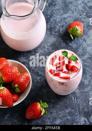 Erdbeerjoghurt mit frischen Beeren aus Glas auf blauem Steingrund. Gesundes Essen- und Getränkekonzept. Stockfoto