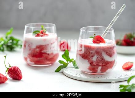 Zwei Gläser Milchshake mit frischen Erdbeeren und Minze. Gesunder sommerlicher Detox-Drink. Grauer Hintergrund. Horizontales Bild. Stockfoto