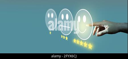 Ein Geschäftsmann bewertet mit einem Smiley-Face-Emoticon auf dem virtuellen Touchscreen, einer Umfrage zur Kundenzufriedenheit und einem Bewertungskonzept für den Kundenservice. Stockfoto