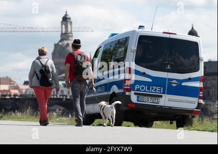 Dresden, Deutschland. Mai 2021. Passanten laufen mit einem Hund an einem Polizeiauto am Elbufer vor der Kulisse der Frauenkirche vorbei. Quelle: Sebastian Kahnert/dpa-Zentralbild/dpa/Alamy Live News Stockfoto