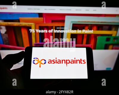 Person, die das Smartphone mit dem Logo des indischen Chemieunternehmens Asian Paints Ltd. Auf dem Bildschirm vor der Website hält. Konzentrieren Sie sich auf die Telefonanzeige. Stockfoto