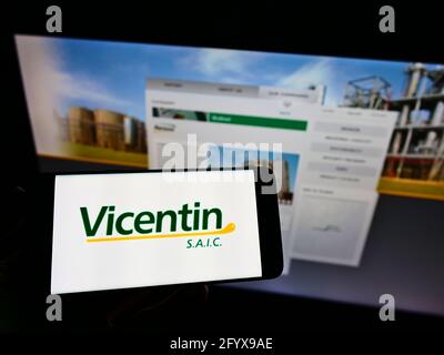 Person, die Mobiltelefon mit dem Logo des argentinischen Konglomerats Vicentin SAIC auf dem Bildschirm vor der Business-Webseite hält. Konzentrieren Sie sich auf die Telefonanzeige. Stockfoto