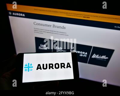 Person, die ein Smartphone mit dem Geschäftslogo des kanadischen Unternehmens Aurora Cannabis Inc. Auf dem Bildschirm vor der Webseite hält. Konzentrieren Sie sich auf die Telefonanzeige. Stockfoto