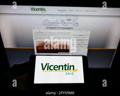 Person, die das Smartphone mit dem Logo des argentinischen Konglomerats Vicentin S.A.I.C. auf dem Bildschirm vor der Website hält. Konzentrieren Sie sich auf die Telefonanzeige. Stockfoto