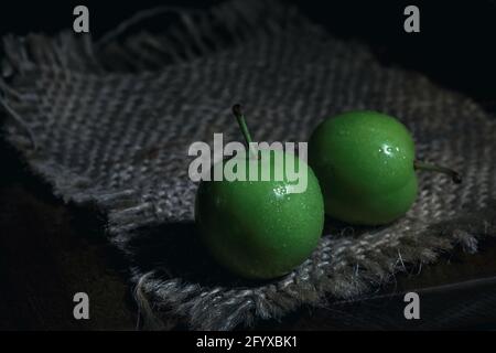 Frische grüne Pflaumen auf hessischer Textur, Nahaufnahme, Stillleben-Fotografie Stockfoto