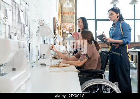 Zwei Modedesigner stehen während der Teamarbeit neben der Schneiderin Stockfoto