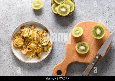 Hausgemachte Kiwi-Chips auf grauem Stein Hintergrund, Heimtrocknung. Snack vegan frei von Zucker. Blick von oben. Stockfoto