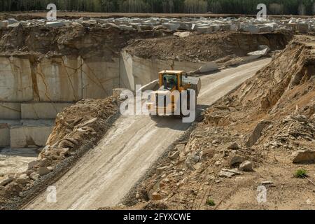 Traktor fährt auf einer schmalen Straße, umgeben von Baustellen und Hölzer Stockfoto
