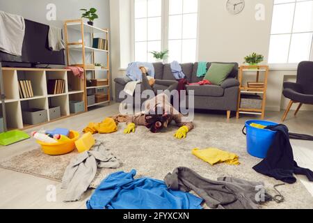 Erschöpfte junge Frau fiel beim Aufräumen auf den Boden Ihr unordentliches Wohnzimmer Stockfoto