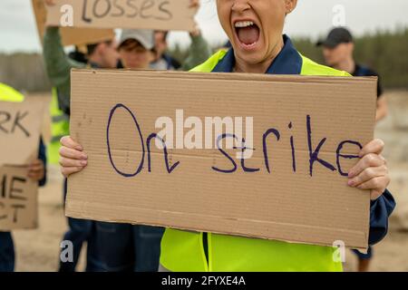 Wütende Baumeisterin schreit, während sie Plakat im Streik trägt Stockfoto