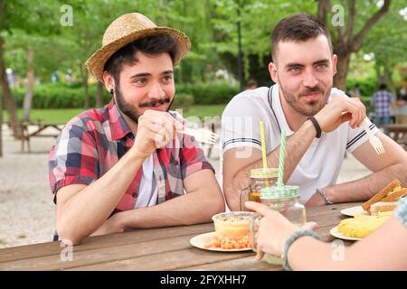 Eine Gruppe von glücklichen Freunden, die Spaß haben und in einem Park essen. Picknick an einem sonnigen Sommertag. Stockfoto