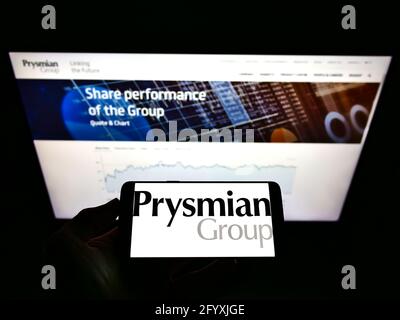 Person, die das Smartphone mit dem Logo des italienischen Elektrokabelherstellers Prysmian S.p.A. auf dem Bildschirm vor der Website hält. Konzentrieren Sie sich auf die Telefonanzeige. Stockfoto