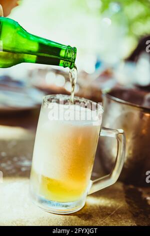 Schaumiges Bier. Ein Glas Bier. In den Becher gießen. Glas voller Schaum. Kaltes Bier auf dem Tisch. Abend im Pub. Bier ist immer eine gute Idee. Stockfoto