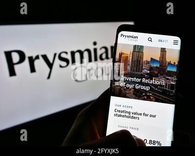 Person, die Mobiltelefon mit Website des italienischen Elektrokabelherstellers Prysmian S.p.A. auf dem Bildschirm mit Logo hält. Konzentrieren Sie sich auf die Mitte des Telefondisplays. Stockfoto