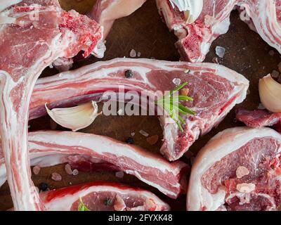 Rohe Lammrippen mit Rosmarin, Knoblauch, Salz und schwarzem Pfeffer zum Grillen Stockfoto