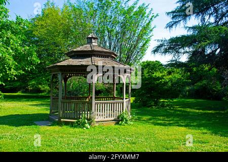 Holzpavillon in den Rutgers Gardens vor dem Hintergrund des neuen Pflanzenwachstums an einem sonnigen Tag im Frühling -03 Stockfoto