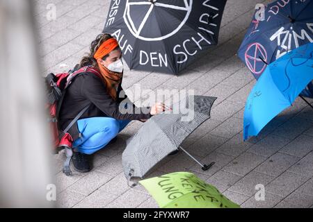 Hamburg, Deutschland. Mai 2021. Ein Aktivist schreibt Slogans auf einen Regenschirm, der vor einer Demonstration auf dem Boden liegt. Verschiedene lokale Gruppen des Extinction Rebellion haben unter dem Motto "Klimakrise auf den Titelseiten" eine bessere Berichterstattung über die Klimakrise bei dezentralen Aktionen vor Medienhäusern gefordert. Quelle: Jonas Walzberg/dpa/Alamy Live News Stockfoto