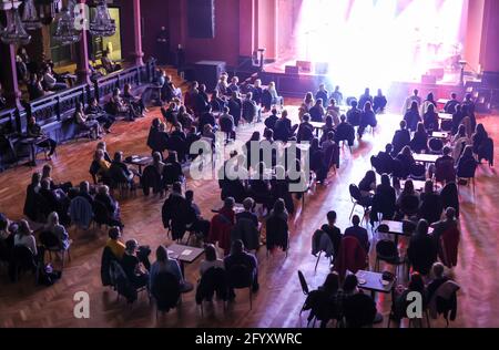 Leipzig, Deutschland. Mai 2021. Konzertbesucher sitzen in einem Konzert des Musikers Fil Bo Riva im Felsenkeller. Hier findet nach eigenen Angaben das erste Indoor-Konzert im Jahr 2021 deutschlandweit statt. Die Halle war mit Stühlen und Tischen eingerichtet und eineinhalb Meter voneinander entfernt. Masken waren überall obligatorisch, außer an ihrem eigenen Platz. Quelle: Jan Woitas/dpa-Zentralbild/dpa/Alamy Live News Stockfoto