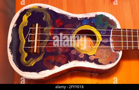 Eine blaue Ukulele von Hand bemalt mit weißen gelb rot blauen Farben. Stockfoto